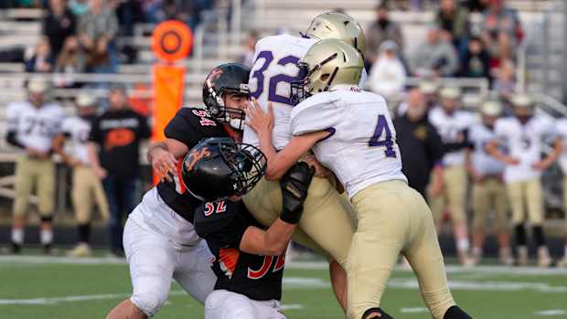 A helmet flies off Kalama's Luke Davidson as he pairs up with Gino Santi to tackle Onalaska's Marshall Haight in a Central 2B League football game on Saturday, Oct. 16, 2021, at Chinooks Stadium in Kalama. Kalama won 58-6. (Joshua Hart/For ScorebookLive)